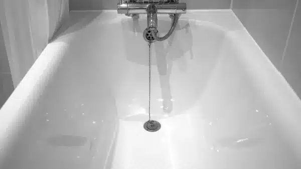 A white bathtub with a metal chain attached to the drain plug.