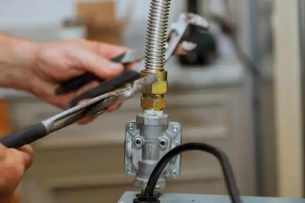 In an industrial setting, skilled hands expertly manipulate a wrench to adjust a nut on a metal pipe during a gas line installation.