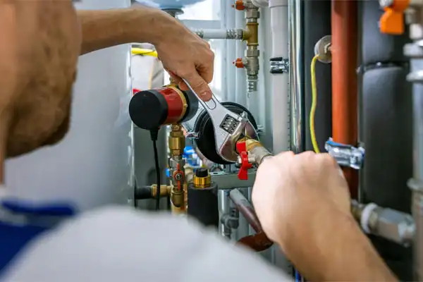 A person uses a wrench to tighten a pipe valve in a plumbing system, ensuring smooth water flow, essential for optimal humidifier installation.