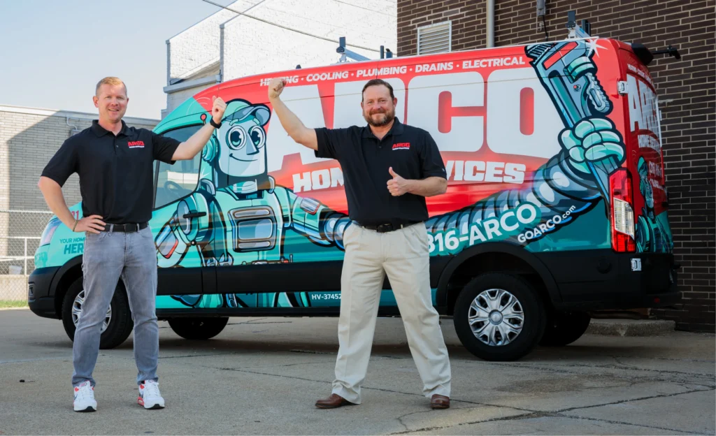 Two men in polo shirts stand smiling in front of a colorful service van with the text "ARCO Home Services." One gestures towards the van while the other gives a thumbs up, capturing the essence of our "About Us" story—friendly, professional, and ready to serve.